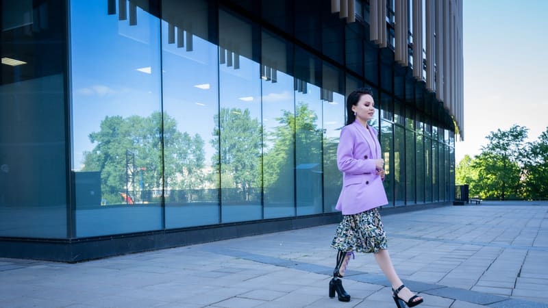 A woman with a prosthetic leg walking past a modern building