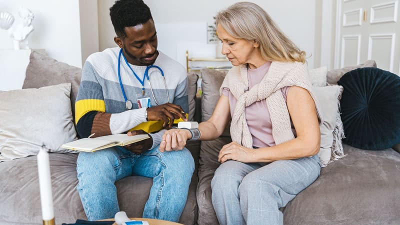 A health professional checking an older woman’s blood pressure at home