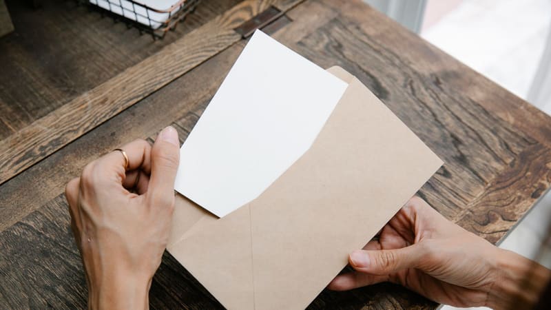 Hands taking a letter out of a brown envelope at a desk