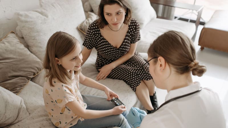 A health professional checking a child’s blood sugar at home