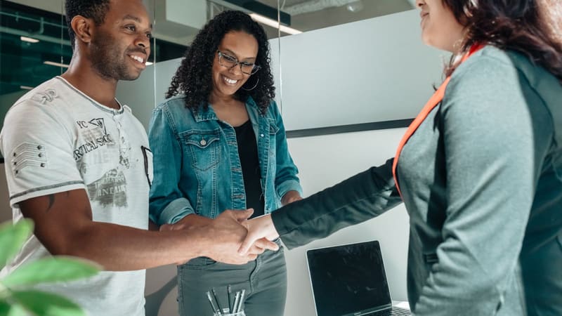 A couple shaking hands with an advisor across a desk