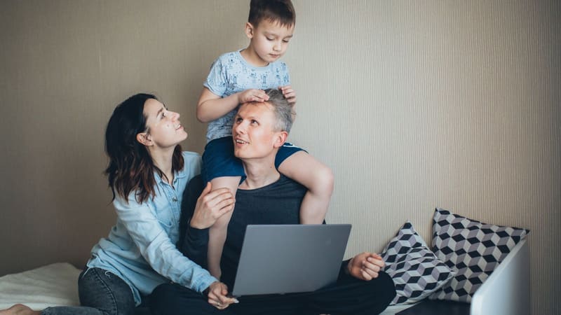 A mother and father holding their young son between them at home