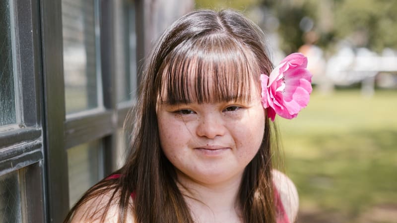 A smiling young woman with a flower in her hair