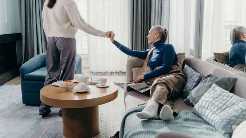 An older woman and her adult daughter relaxing together on a sofa at home
