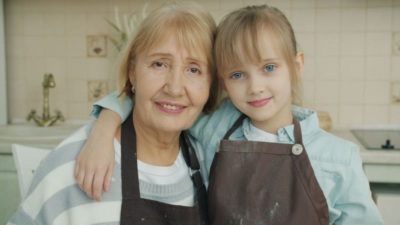 A grandmother and her granddaughter baking together in a kitchen