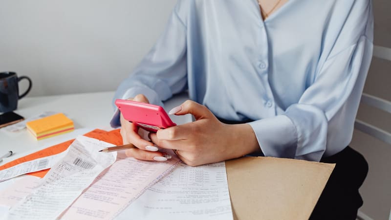 A woman adding up receipts with a calculator at a desk